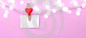 Happy Valentine`s Day background banner - White paper note hang on wooden clothes pegs with wooden hearts on a string isolated on