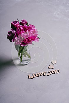 Happy Valentine`s Day. A bouquet of pink peonies and a wooden inscription I love you