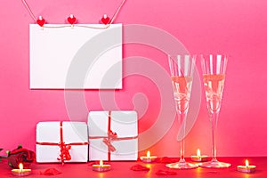 Happy ValentineÃÂ´s day card rnwith hearts, gifts, rose, rncandles and  two glasses of champagne on pink background. San Valenti