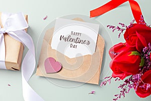 Happy valentine\'s day card in kraft envelope with heart, gift box and rose on pastel background