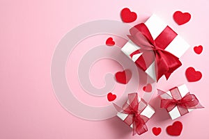 Happy Valentine`s Day card mockup. White gift boxes with red ribbon bow and red hearts on pink background. Flat lay, top view,