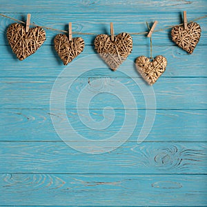 Happy Valentine`s Day! Decorative wicker hearts of gold color on a blue wooden background