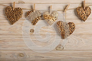 Happy Valentine`s Day! Decorative wicker hearts of gold color on a light wooden background