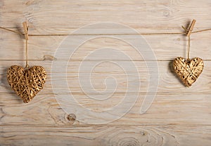 Happy Valentine`s Day! Decorative wicker hearts of gold color on a light wooden background