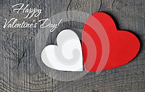 Happy Valentine`s Day greeting card.Decorative red and white wooden hearts on a grey wooden background.