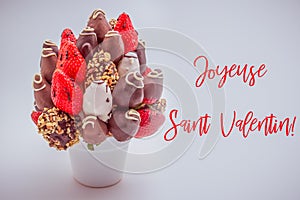 Happy valentine`s day greeting card in French that reads Joyeuse Saint Valentin with red lettering; A bundle of edible flowers,