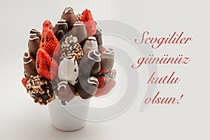 Happy valentine`s day greeting card that reads Sevgililer gununuz kutlu olsun with red lettering; A bundle of edible flowers,