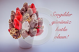 Happy valentine's day greeting card that reads Sevgililer gununuz kutlu olsun with red lettering; A bundle of edible flowers,