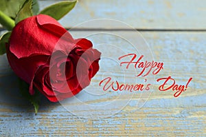 Happy Valentine`s Day greeting card.Red rose on a blue wooden background