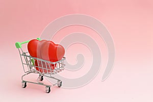 Happy Valentine`s Day or Mother`s Day greeting card with red hearts in a shopping cart on pink background.Banner for your store