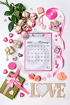 Happy Valentine`s day. Roses flowers, LOVE text, hearts, gifts and decorative items in pink pastel colors. February 2021 calendar