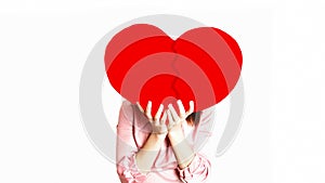 Happy Valentine`s day! woman in pink holding a big red broken heartin her hands hiding her face on white background. concept of
