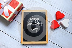 Happy Valentine`s day written on a chalkboard with wooden handraft heart and box