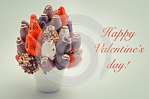 Happy Valentine`s greeting card with red lettering; A bundle of edible flowers, arrangement of strawberries covered with chocolat