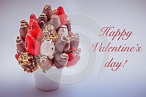 Happy Valentine`s greeting card with red lettering; A bundle of edible flowers, arrangement of strawberries covered with chocolat