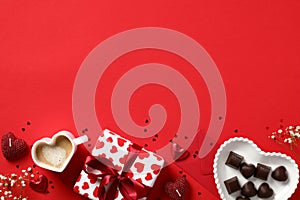 Happy Valentines Day background. Frame made of gift box, candy, heart shaped cup of coffee, candles on red table. Flat lay, top