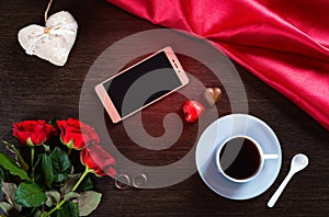 Happy Valentines Day background with wedding rings, rose flowers, smartphone, cup of coffee and chocolate candy