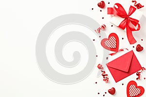 Happy Valentines Day composition. Flat lay, top view red envelope, gift box with red ribbon bow, hearts, party streamers, confetti
