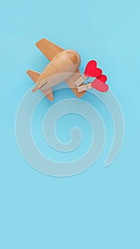 Happy Valentines day. Eco wooden children`s plane on a blue background with red heart