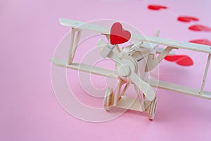 Happy Valentines day. wooden children`s plane on a pink background with red heart, and garland in the shape of a heart