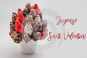 Happy valentines day greeting card in French that reads Joyeuse Saint Valentin with red lettering; A bundle of edible flowers,
