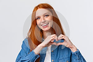 Happy valentines day, love. Cute and tender romantic redhead girlfriend showing heart sign, confess in sympathy, express