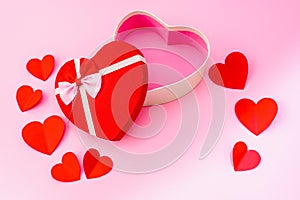 Happy valentines day, opened heart shape gift box with ribbon and small paper hearts, on pink background, top view