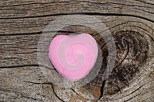 Happy Valentines day with single pink heart shaped candy on rust