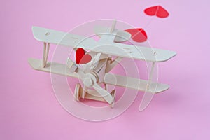 Happy Valentines day. wooden children`s plane on a pink background with red heart, and garland in the shape of a heart