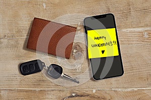 Happy Valentines romantic and sweet handwritten note on yellow posit stick to mobile phone next to car key and leather wallet in