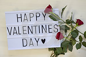 Happy Valentinesday written on a lightbox with roses photo