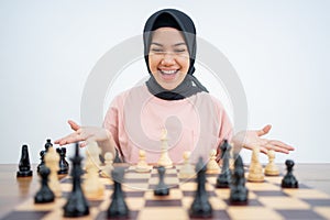 Happy veiled woman with right move while playing chess