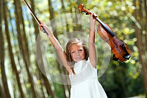 Happy violinist raising violin outdoors.