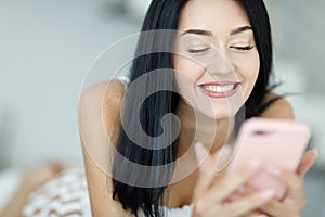Happy vivacious young woman reading a text message on her mobile