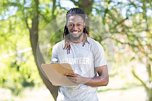 Happy volunteer in the park holding clipboard