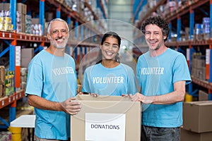 Happy volunteers are smiling and posing with a donations box