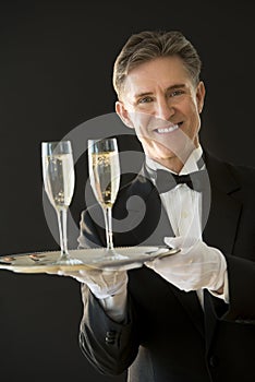 Happy Waiter Holding Serving Tray With Champagne Flutes