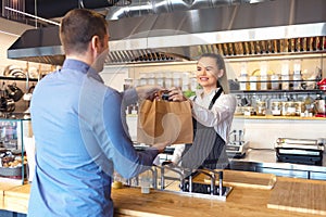 Happy waitress waring apron serving customer at counter in small family eatery restaurant