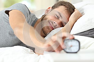 Happy wake up of a happy man stopping alarm clock