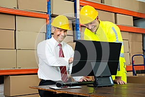 Happy Warehouse Worker And Manager Using Computer