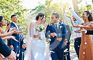 Happy, wedding ceremony and couple walking with petals and guests throw in celebration of romance. Romantic, flowers and