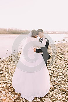 Happy wedding couple, bride and groom embracing face-to-face neat river