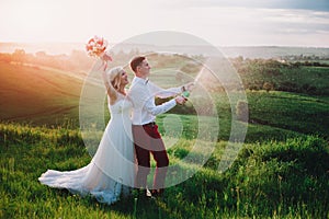 Happy wedding couple with buttle of champaine and splashes of champagne