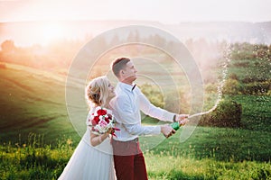 Happy wedding couple with buttle of champaine and splashes of champagne