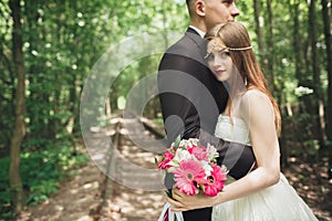 Happy wedding couple charming groom and perfect bride posing in park