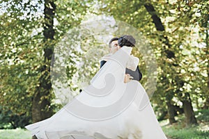 Happy wedding couple charming groom and perfect bride posing in park