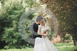 Happy wedding couple charming groom and perfect bride posing in park