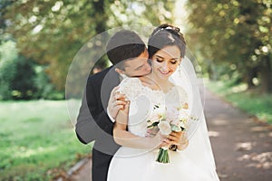 Happy wedding couple charming groom and perfect bride posing in park