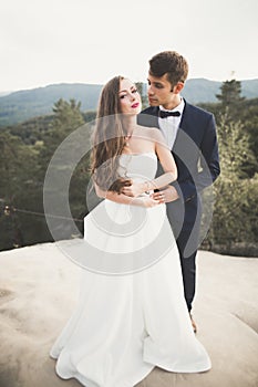 Happy wedding couple kissing and hugging near a high cliff