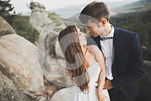 Happy wedding couple kissing and hugging near a high cliff